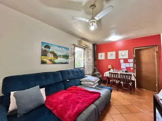 Sala de estar com sofá azul e parede vermelha em imóvel no Brasil.