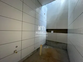 Corredor interno com paredes brancas e piso de concreto.