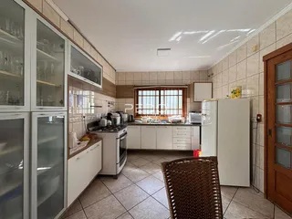 Foto de uma cozinha com armários brancos e piso de cerâmica.