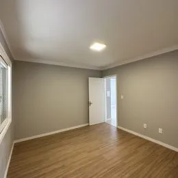 Foto de um ambiente interno com piso de madeira clara e paredes neutras.