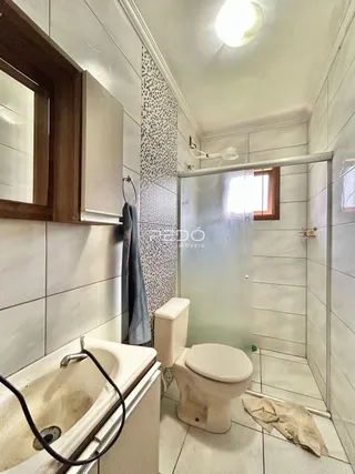 Foto interna de um banheiro com box de vidro e banheira.