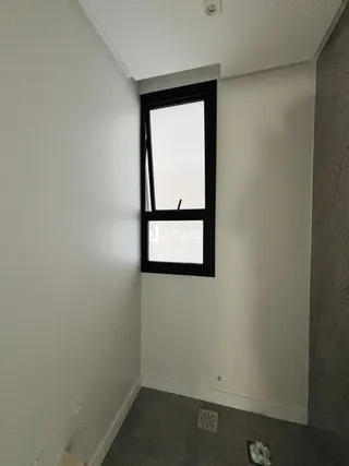 Vista de um corredor interno com parede branca e janela escura.