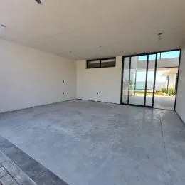 Foto de um espaço interno amplo com piso de concreto e portas de vidro.