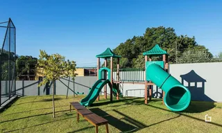 Área externa com gramado e equipamentos de lazer.