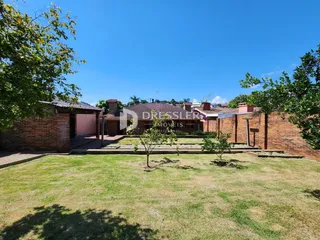 Vista externa de uma propriedade com muro de tijolos e gramado verde.