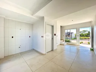Ambiente interno de uma sala ampla com piso claro e paredes brancas.