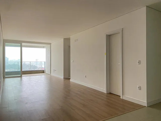 Sala ampla com piso de madeira e vista da cidade.
