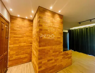 Ambiente interno com paredes de tijolo aparente e piso de madeira.