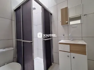 Banheiro com revestimento de azulejos brancos e bancada de madeira.