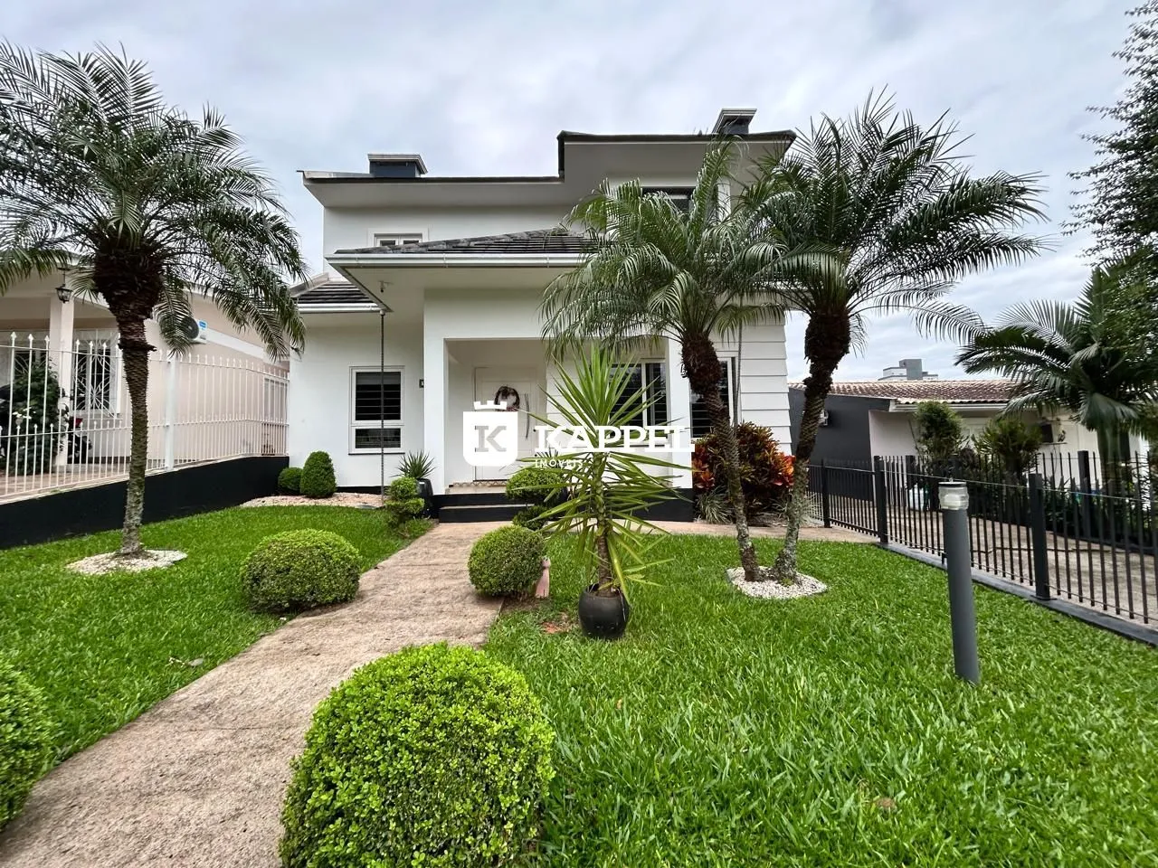 Fachada de uma casa moderna com jardim e palmeiras em Lajeado.