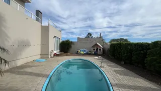 Foto da área externa mostrando uma piscina e um pátio pavimentado.