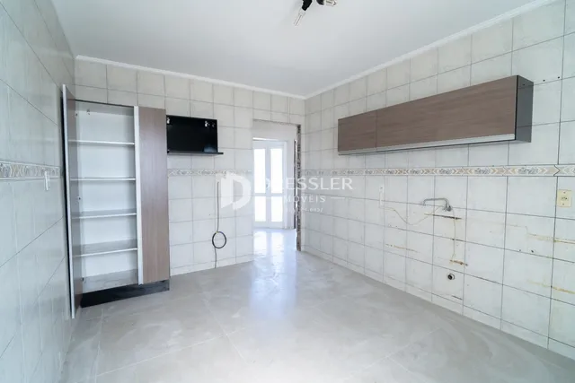 Corredor interno com paredes de azulejo claro e piso de cerâmica.