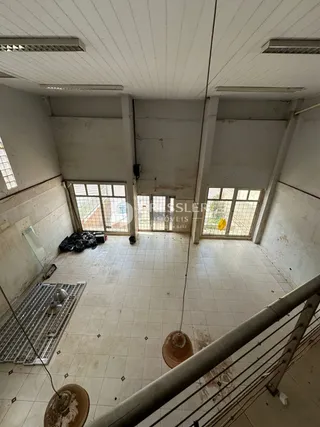 Vista interna de um ambiente com teto de estrutura exposta e piso de cerâmica.