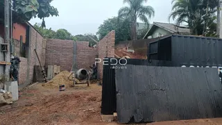 Vista externa de uma propriedade em construção com muros de tijolo e cerca de metal.