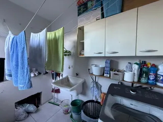 Uma área de serviço com roupas penduradas e uma máquina de lavar.