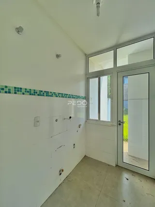 Vista interna de um corredor com revestimento cerâmico branco e portas de vidro.
