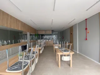 Uma sala de jantar com mesas de madeira e cadeiras alinhadas.