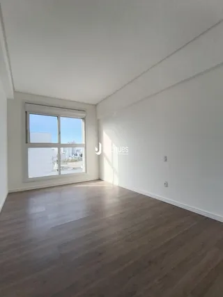 Ambiente interno de uma sala com piso de madeira e grande janela.
