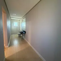 Corredor interno com paredes claras e piso claro.