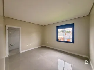 Interior de uma sala de estar com paredes claras e piso de grande formato.