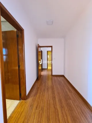 A foto mostra um corredor interno com piso de madeira.