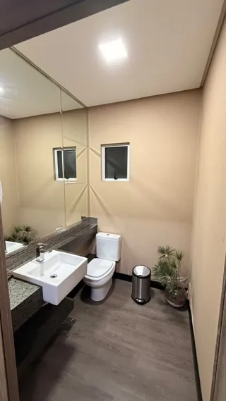 Foto de um banheiro interno com piso de madeira e louças brancas.