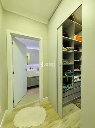 Hall de entrada mostrando um corredor com um guarda-roupa grande.