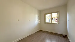 Ambiente interno de uma sala com piso de madeira clara e paredes brancas.