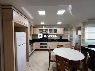 Cozinha com armários claros e mesa de jantar de madeira.