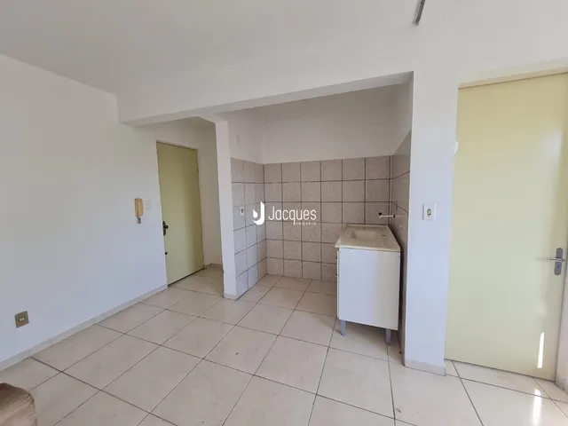 Hall de entrada com acesso a um banheiro revestido de azulejos.