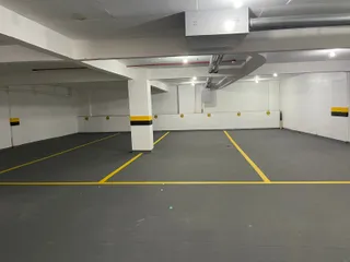 Foto de um espaço interno com piso de concreto e marcações amarelas.