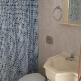 Foto de um banheiro com pia e revestimento de azulejos brancos.