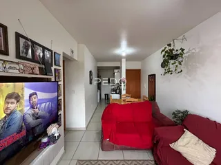Sala de estar com sofá vermelho e televisão na parede em um imóvel em Lajeado.