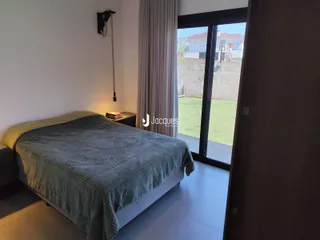 Quarto com cama e porta de vidro abrindo para o jardim.