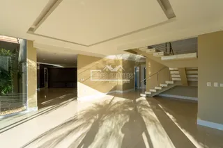A foto mostra um corredor interno com piso claro e teto alto.