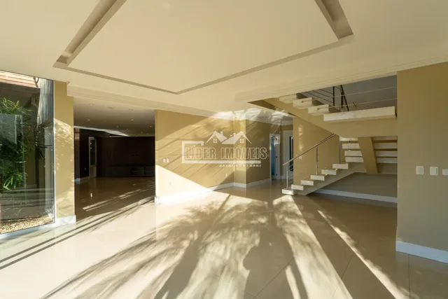 A foto mostra um corredor interno com piso claro e teto alto.