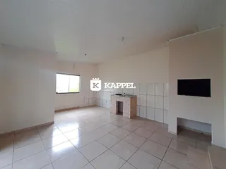 Sala ampla com piso de cerâmica e paredes brancas.