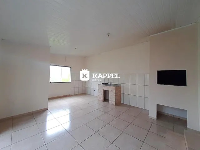 Sala ampla com piso de cerâmica e paredes brancas.