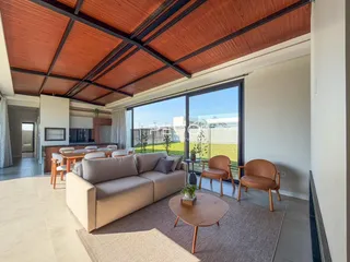 Sala de estar com teto de madeira e vista para o quintal através de grandes janelas.