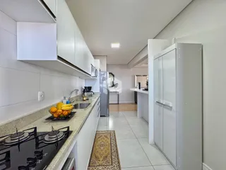 Cozinha moderna com armários brancos e piso claro.