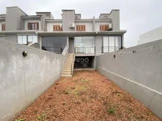 Vista externa de uma residência moderna em Lajeado, Brasil, com muro frontal e jardim.