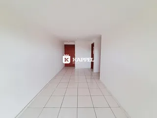 Uma foto de um corredor interno com paredes brancas e piso de cerâmica.