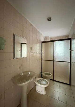 Foto de um banheiro com paredes de azulejo branco e louças sanitárias.