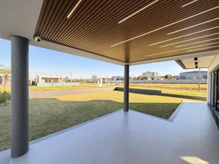 Vista de uma área externa coberta com piso de cerâmica e gramado.
