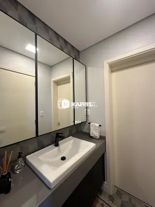 Foto interna de um banheiro com bancada e espelho.