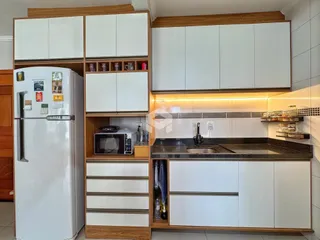 Vista da cozinha com armários brancos e madeira em Lajeado.