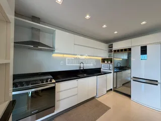 Cozinha moderna com armários brancos e bancadas escuras.