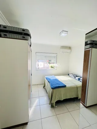 Quarto com cama e armários brancos em um apartamento.