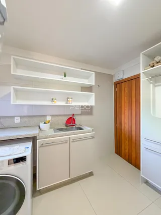 Uma cozinha moderna com armários brancos e bancadas claras.