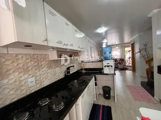 Uma cozinha moderna com armários brancos e bancadas escuras.